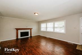 Indianapolis house for rent - A room with a fireplace and wooden floors.