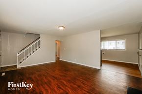 Indianapolis house for rent - A spacious room with wooden floors and a staircase on the left side.