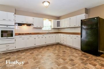 Florissant house for rent - a kitchen with white cabinets and a black refrigerator