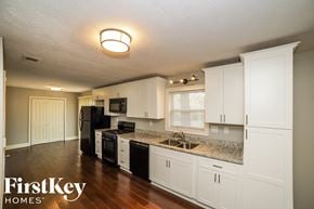 Douglasville house for rent - a kitchen with white cabinets and granite counter tops and black appliances