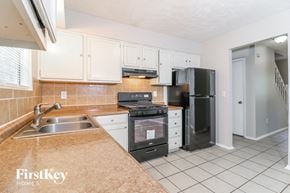 Lithonia house for rent - a kitchen with white cabinets and black appliances