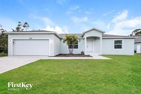 Port Charlotte house for rent - A white house with a garage and a tree in front of it.