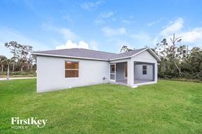 Port Charlotte house for rent - A white house with a grey roof is surrounded by green grass.