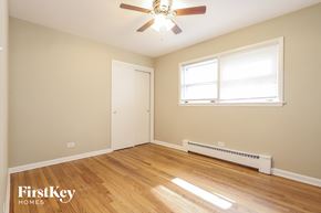 Chicago house for rent - a bedroom with wood floors and a ceiling fan