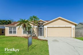Palmetto house for rent - a beige house with a garage and palm trees