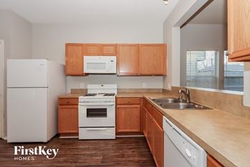 Katy house for rent - A kitchen with wooden cabinets and white appliances.