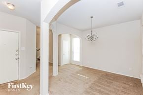 Fort Worth house for rent - a spacious living room and dining room with white walls and a beige carpet