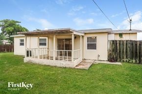 Sunrise house for rent - the exterior of a small house with a porch and a grass yard