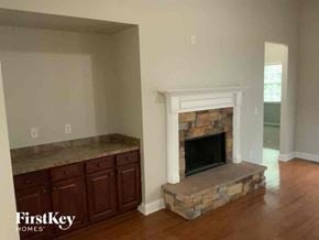 Flowery Branch house for rent - an empty living room with a stone fireplace and wooden floors
