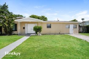 Sunrise house for rent - a small beige house with a lawn and a white door