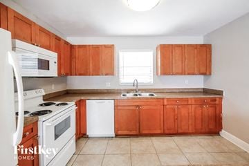 Sunrise house for rent - a kitchen with wooden cabinets and white appliances