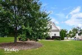 Flowery Branch house for rent - A tree in a circle of dirt with a white house in the background.
