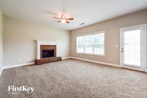 Flowery Branch house for rent - A spacious room with a fireplace and a ceiling fan.