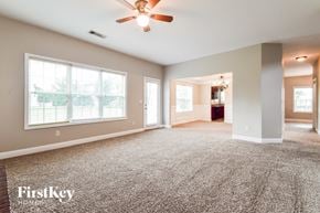 Flowery Branch house for rent - A spacious living room with a carpeted floor and a ceiling fan.