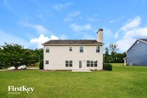 Flowery Branch house for rent - A white house with a chimney is surrounded by a grassy lawn.