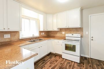Kansas City house for rent - A kitchen with white cabinets and a white stove top oven.