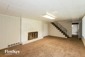 Kansas City house for rent - A spacious room with a fireplace and a staircase.