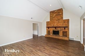 Memphis house for rent - A large empty room with a brick fireplace and wooden floors.