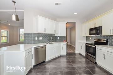 Olive Branch house for rent - A kitchen with white cabinets and a black stove top oven.