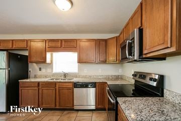 Indianapolis house for rent - a kitchen with wood cabinets and black appliances and granite counter tops