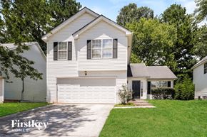 Lithonia house for rent - A white house with a garage is surrounded by greenery.