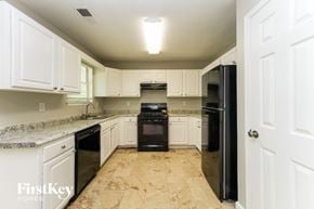 Lithonia house for rent - A kitchen with black appliances and white cabinets.