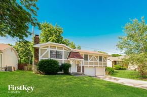 Grandview house for rent - A house with a white and beige exterior is surrounded by greenery and has a clear blue sky above.