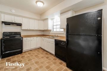 Grandview house for rent - A black refrigerator in a kitchen with white cabinets.