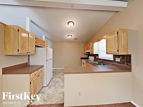 Charlotte house for rent - A kitchen with white appliances and wooden cabinets.