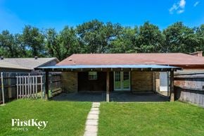 Garland house for rent - A house with a brown roof and a white door is surrounded by a fence and green grass.