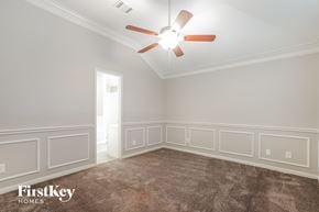Katy house for rent - a bedroom with white wainscoting and a ceiling fan