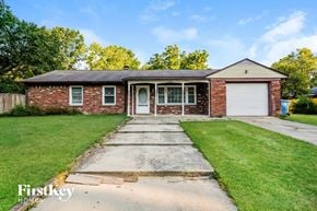 Indianapolis house for rent - a brick house with a white garage door and a lawn