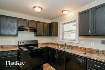 Indianapolis house for rent - full view of kitchen with black appliances and granite counter tops and dark wood cabinets