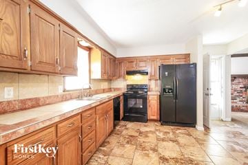 Grandview house for rent - a kitchen with wooden cabinets and a black refrigerator