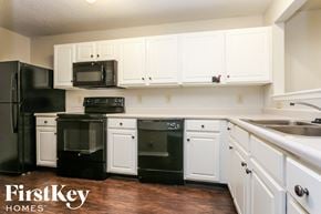 Indianapolis house for rent - A kitchen with black appliances and white cabinets.