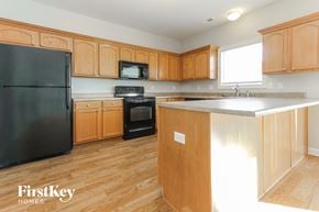 Indianapolis house for rent - a kitchen with wooden cabinets and a black refrigerator