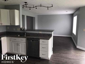 Morrow house for rent - a renovated kitchen with white cabinets and black counter tops