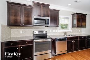 Whitsett house for rent - a kitchen with dark wood cabinets and stainless steel appliances