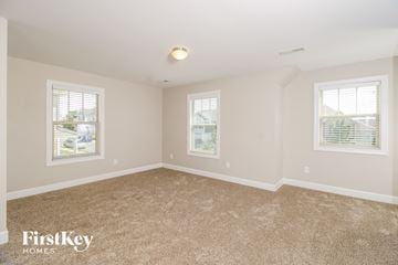 Whitsett house for rent - a spacious living room with carpet and two windows