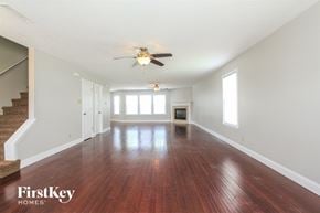 Indianapolis house for rent - A spacious room with wooden floors and a staircase on the left side.