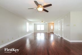 Indianapolis house for rent - A spacious room with wooden floors and a ceiling fan.