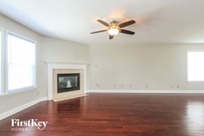 Indianapolis house for rent - A room with a fireplace and a ceiling fan.