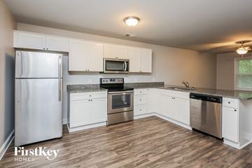 Gainesville house for rent - a kitchen with white cabinets and stainless steel appliances