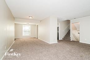 Florissant house for rent - A spacious room with a staircase leading to another room.