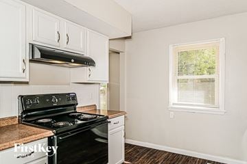 Florissant house for rent - A kitchen with a black stove top oven and white cabinets.
