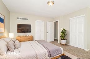 Florissant house for rent - A bedroom with a large bed and a flat screen TV mounted on the wall.