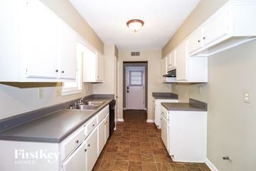 Memphis house for rent - a kitchen with white cabinets and counters and a door to a hallway