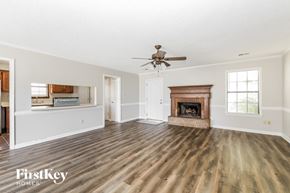 Memphis house for rent - an empty living room with a fireplace and a ceiling fan