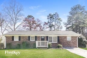 Lithia Springs house for rent - A brick house with a porch and a tree with red leaves in front of it.