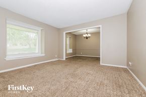 Grandview house for rent - A spacious room with a carpeted floor and a chandelier hanging from the ceiling.
